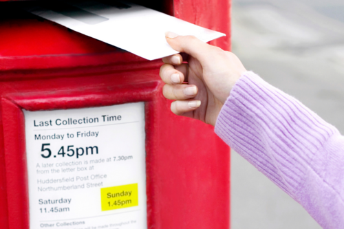 Person posting an envelope into a postbox