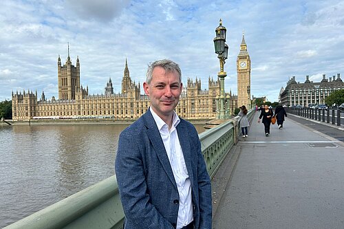 Will Forster with Houses of Parliament behind him