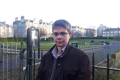 Councillor Jack Caldwell in front of a graffitied sign in Dalmeny Street Park