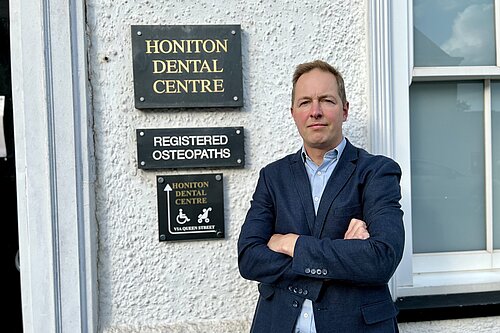 Richard Foord standing in frnt of the sign for Honiton Dental Centre