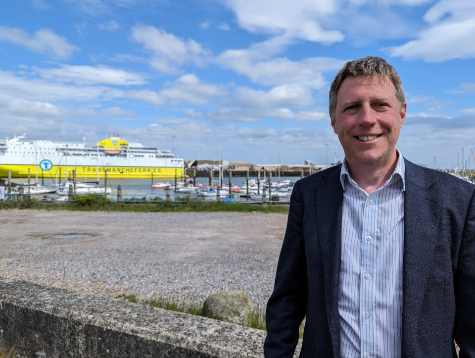 James looking happy against a background of Newhaven Harbour with a ferry and a lot of yachts.